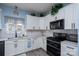 Bright kitchen features white cabinetry, stainless appliances, and a subway tile backsplash at 240 Hillcrest Dr, Harrisburg, NC 28075