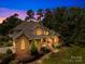 Charming two-story brick home with manicured landscaping, inviting porch, and mature trees at dusk at 266 Riverwood Rd, Mooresville, NC 28117