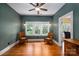 Bright bedroom with hardwood floors, ceiling fan, view of mature trees from triple window, and rocking chairs at 409 S Grove St, Lincolnton, NC 28092