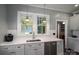 Bright kitchen sink area features stainless steel dishwasher, white subway tile, white counters, and a backyard view at 409 S Grove St, Lincolnton, NC 28092