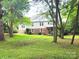 View of home exterior showcasing a metal roof, brick foundation and large treed back yard at 423 N Cedar St, Lincolnton, NC 28092
