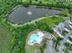 Aerial view of a pool and neighborhood pond surrounded by lush green landscaping at 4915 Juniper Grove Sw Ct, Concord, NC 28027