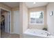 Bright bathroom featuring a large window and a corner soaking tub at 4915 Juniper Grove Sw Ct, Concord, NC 28027