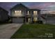 Inviting home exterior at dusk with warm interior lighting and a well-manicured front lawn at 4915 Juniper Grove Sw Ct, Concord, NC 28027