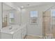 Bathroom with double vanity sinks, large mirror, window, and glass-enclosed shower at 5332 Orchid Bloom Dr, Indian Land, SC 29707