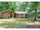 Charming brick home featuring mature trees, an inviting front porch, and lush landscaping for a serene curb appeal at 541 Greenway St, Davidson, NC 28036