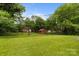Large backyard with green grass, mature trees and a storage shed at 5918 Barrington Dr, Charlotte, NC 28215