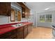 Cozy kitchen featuring wood cabinets, red countertops, and a stainless steel double sink at 5918 Barrington Dr, Charlotte, NC 28215