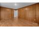 Empty Living Room with wood paneled walls, hardwood floors, and a door to another room at 5918 Barrington Dr, Charlotte, NC 28215