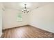 Empty dining room with wood-look flooring, a window, and a modern chandelier, ready for personalization at 6221 Round Hill Rd, Charlotte, NC 28211