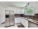 Bright kitchen features stainless steel refrigerator, white cabinets, and a window with natural light at 6221 Round Hill Rd, Charlotte, NC 28211