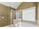 Bright bathroom features a soaking tub and glass enclosed shower, next to a sunlit window at 6619 Hermsley Rd, Charlotte, NC 28278