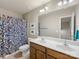 Bathroom features a wood vanity with double sinks, decorative blue shower curtain, and a large mirror at 6619 Hermsley Rd, Charlotte, NC 28278