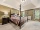 Spacious main bedroom featuring a tray ceiling, four-poster bed, and ample natural light at 6619 Hermsley Rd, Charlotte, NC 28278