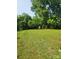 Large backyard with green grass, mature trees, and a small storage building at 76 Sumner Nw Ave, Concord, NC 28027