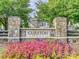 Welcoming neighborhood entrance with stone pillars and colorful flower beds at 8725 Soaring Eagle Ln, Waxhaw, NC 28173