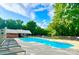 Sparkling pool surrounded by lounge chairs and lush greenery under a bright, partly cloudy sky at 1035 Wexford Nw Pl, Concord, NC 28027