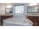 Bright bathroom featuring double sinks, a large tub with tile surround and framed mirrors at 1211 Gold Rush Ct, Fort Mill, SC 29708