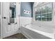 Bright bathroom featuring a soaking tub, tiled walls, and a window, creating a serene and spa-like atmosphere at 1305 Creekview Dr, Gastonia, NC 28052