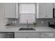 Close-up of kitchen counter with stainless sink, gray backsplash, and white cabinets at 161 Pampas Pl, Statesville, NC 28625