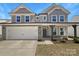 Charming two-story home featuring a two-car garage and covered entryway with stone and gray shingle exterior accents at 163 W Heart Pine Ln, Statesville, NC 28677