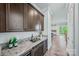 Elegant wet bar with granite countertops, wine refrigerator and dark wood cabinets at 1702 Batson Creek Ln, Weddington, NC 28104