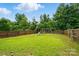 Large fenced backyard with lush green grass, trees, and swing set at 2234 Dion Ave, Charlotte, NC 28212