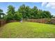 Large, grassy backyard featuring a wooden fence, a swing set, and mature trees for a private outdoor space at 2234 Dion Ave, Charlotte, NC 28212