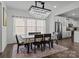 Elegant dining room with a crystal chandelier, natural light, and an adjacent modern kitchen area at 3127 Pinehills Way, Mount Holly, NC 28120