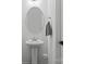 Well-lit powder room featuring a pedestal sink, round mirror, and modern towel rack at 3127 Pinehills Way, Mount Holly, NC 28120