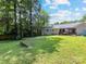Spacious backyard with a garden bed and lush green lawn, surrounded by mature trees at 3530 Woodleaf Rd, Charlotte, NC 28205