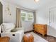 Cozy bedroom featuring a white armchair, wooden dresser, and natural light from the window at 3530 Woodleaf Rd, Charlotte, NC 28205