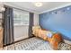 bedroom with a cozy bed, neutral rug, and a bright blue accent wall decorated with festive ornaments at 3530 Woodleaf Rd, Charlotte, NC 28205