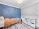 bedroom featuring twin bed, neutral rug, and a bright blue accent wall decorated with festive ornaments at 3530 Woodleaf Rd, Charlotte, NC 28205