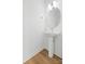A modern pedestal sink with a round mirror in a minimalist bathroom with hardwood floors at 3924 Hager Dr, Charlotte, NC 28208