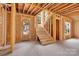 Unfinished interior featuring a wooden staircase and front door framed by exposed studs and beams at 4918 Buckingham Dr, Charlotte, NC 28209