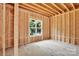 Unfinished bedroom featuring exposed studs, beams, and a large window overlooking the backyard at 4918 Buckingham Dr, Charlotte, NC 28209