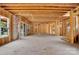 Unfinished interior featuring exposed studs, beams, staircase, and sliding glass doors to a patio at 4918 Buckingham Dr, Charlotte, NC 28209