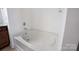 Bright white bathtub with tile surround and modern faucet fixtures in renovated bathroom at 5008 Social Cir, Fort Mill, SC 29707