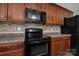 Close-up of the kitchen featuring black appliances, tile backsplash, and wood cabinetry at 5008 Social Cir, Fort Mill, SC 29707