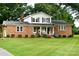 Charming two-story brick home features a covered front porch, manicured lawn, and mature trees at 7448 Forney Hill Rd, Denver, NC 28037