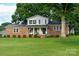 Charming two-story brick home features a covered front porch, manicured lawn, and mature trees at 7448 Forney Hill Rd, Denver, NC 28037