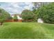 Large backyard featuring green grass, mature landscaping, and a small storage shed at 8115 Wilburn Ct, Charlotte, NC 28277