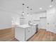 Bright kitchen featuring white cabinets, pendant lights, large island, and hardwood floors open to the living area at 8315 Adrian Ct, Charlotte, NC 28270