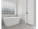 Elegant bathroom with a standalone tub, glass block window, and marble accents for a luxurious bathing experience at 8921 Whittingham Dr, Waxhaw, NC 28173