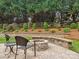 A stone fire pit on a stone patio featuring landscaping and a green backdrop of trees and bushes at 8921 Whittingham Dr, Waxhaw, NC 28173