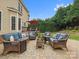 A stone patio with blue wicker furniture, matching pillows, green landscaping, and manicured green hedges at 8921 Whittingham Dr, Waxhaw, NC 28173