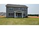 Back exterior showcasing a covered porch and a well-maintained lawn and an open field behind the property at 119 Tonbridge Way # Haf0033, Mooresville, NC 28115