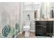Well-lit bathroom features a patterned shower curtain, a black vanity with storage, and tiled floors at 12014 Belmont Mansion Dr, Charlotte, NC 28273