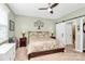 Cozy bedroom features a ceiling fan, decorative tree art, and sliding barn door to an en-suite bathroom at 12014 Belmont Mansion Dr, Charlotte, NC 28273